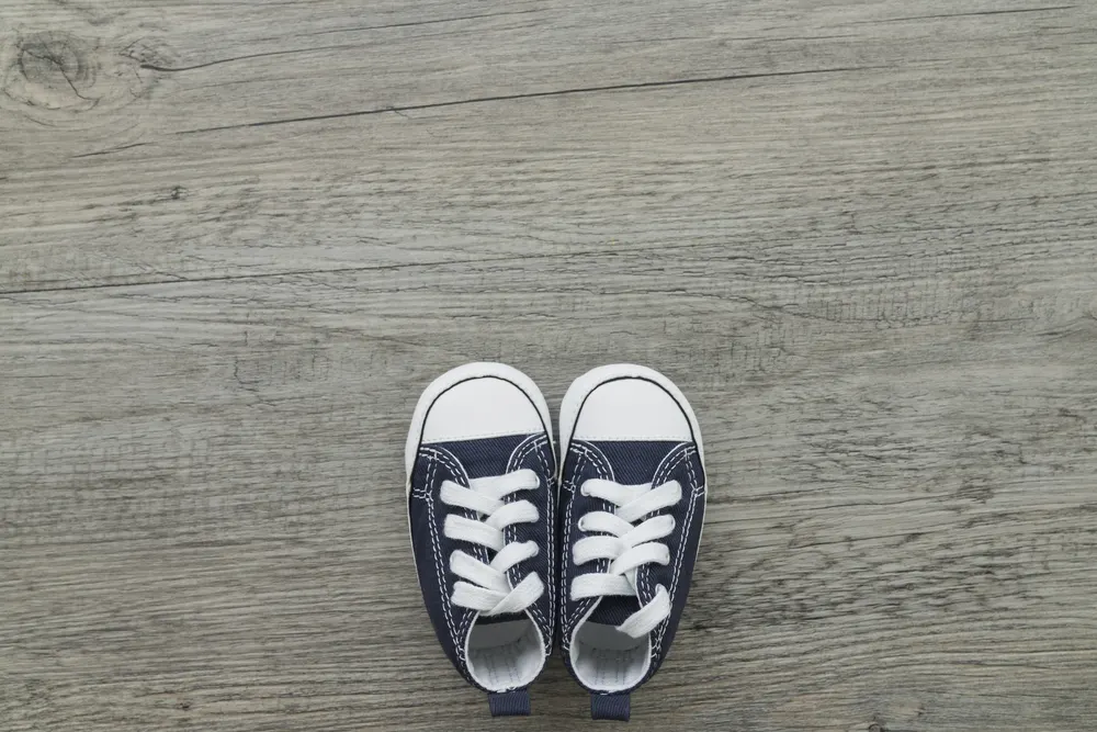 Ein Paar kleine dunkelblaue Kinderturnschuhe auf einem grauen Holzboden